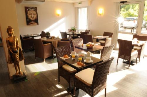 un restaurant avec des tables, des chaises et une statue dans l'établissement Hôtel du Moulin, à Niort