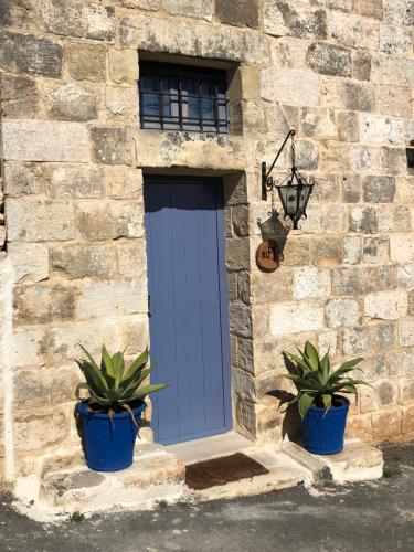 a blue door on a stone building with two potted plants at Ta Skorba Farmhouse Mgarr in Mġarr
