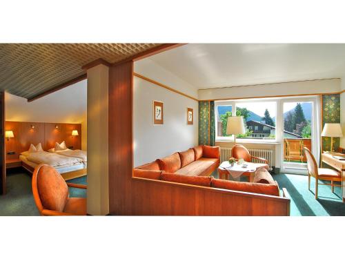 a hotel room with a couch and a bed and a mirror at Steinbach-Hotel in Ruhpolding