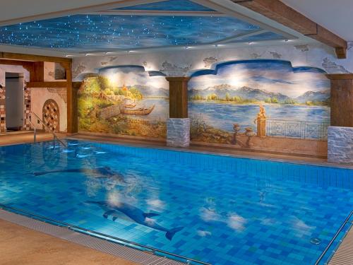 a large swimming pool in a building with a mural at Steinbach-Hotel in Ruhpolding