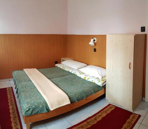 a small bedroom with a bed and a cupboard at Muskátli Üdülőház in Parádfürdő-Peres