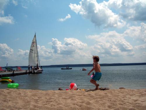 a young boy walking on a beach with a sail boat at Aparthotel Am See in Plau am See