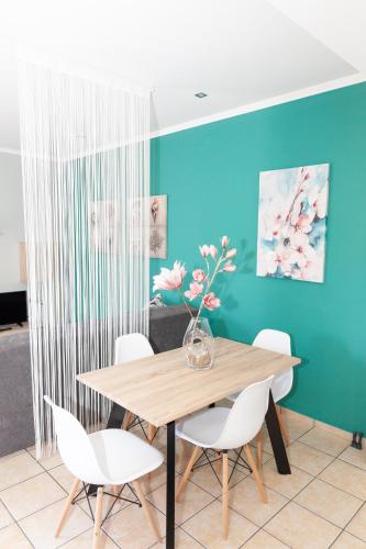 a dining room table with white chairs and a vase with flowers at Nina Apartment in Chania Town