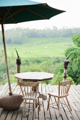 a table and two chairs and an umbrella on a deck at Bambu Indah Resort in Ubud