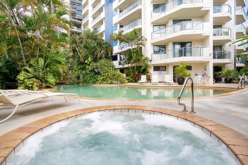een zwembad met een hot tub voor een gebouw bij 181 The Esplanade in Cairns