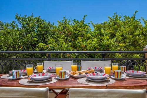 a wooden table with plates of food and glasses of orange juice at Lina's Amazing House in Ialysos in Ixia