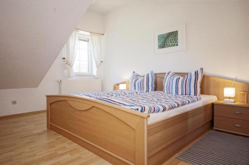 ein Schlafzimmer mit einem Holzbett mit gestreiften Kissen in der Unterkunft Ferienwohnungen beim Fischer und sin Fru in Klein Zicker