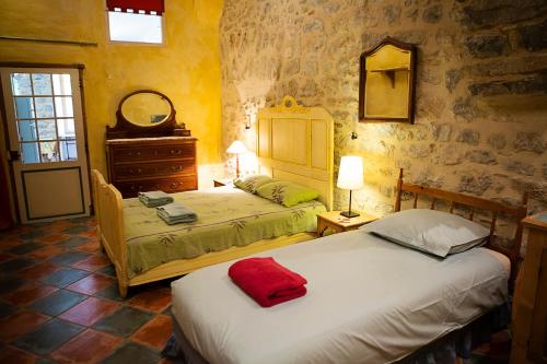 a bedroom with two beds and a dresser and a mirror at The Balcony Gîte - Riverside Lagrasse in Lagrasse