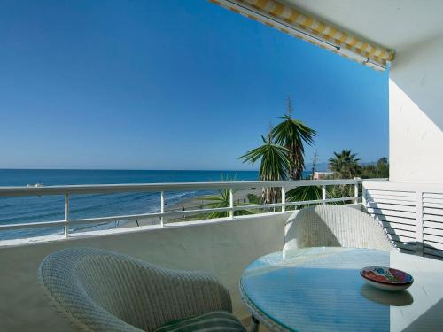 een tafel en stoelen op een balkon met uitzicht op het strand bij Apartment Playa Real by Interhome in Marbella