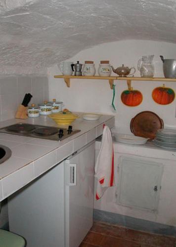 a kitchen with a counter top with dishes on shelves at Castello di Grotti in Corsano