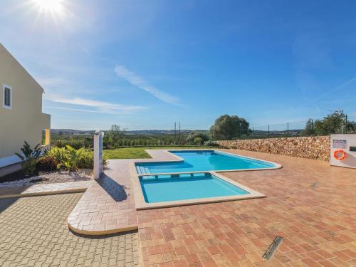a swimming pool in a yard with a brick patio at Holiday Home Vila Caravela by Interhome in Estevais