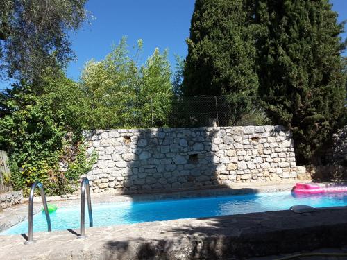 - une piscine à côté d'un mur en pierre et d'arbres dans l'établissement 