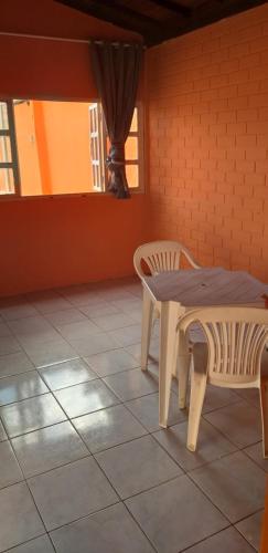 stół i 2 krzesła na podłodze wyłożonej kafelkami w obiekcie Acomodaçaoes koynonya w mieście Sete Lagoas