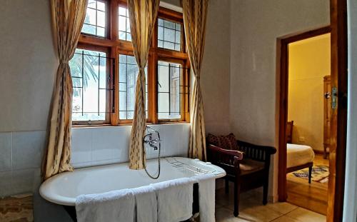 a bathroom with a bath tub with a window at Redbourne Hilldrop Guesthouse B&B in Cape Town