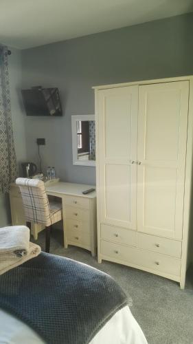a bedroom with a desk and a white cabinet at The Buck Inn in Buckden