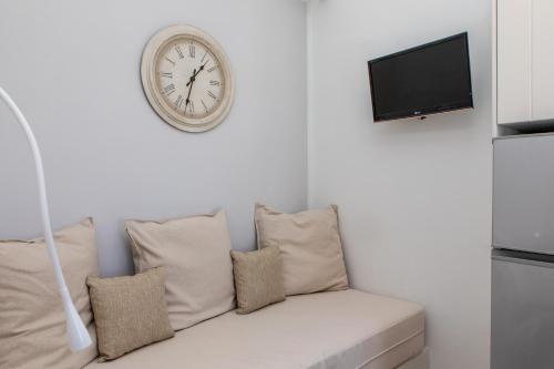 a clock on a wall above a couch with pillows at Naxos Illusion Nikos Verikokos in Naxos Chora
