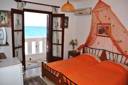 a bedroom with an orange bed with a view of the ocean at Christina Pansion in Kokkari