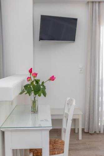 a vase of flowers on a glass table with a chair at Naxos Illusion Nikos Verikokos in Naxos Chora