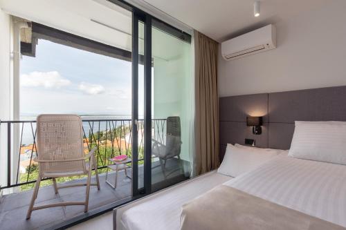 a bedroom with a bed and a balcony with a view at Paviljoni Omorika in Crikvenica