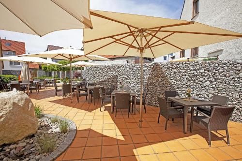 a patio with tables and chairs with umbrellas at Hotel Hirsch in Leonberg