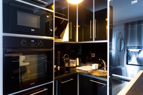 a kitchen with black cabinets and a microwave and a sink at Apartmani Pezerović in Soko Banja