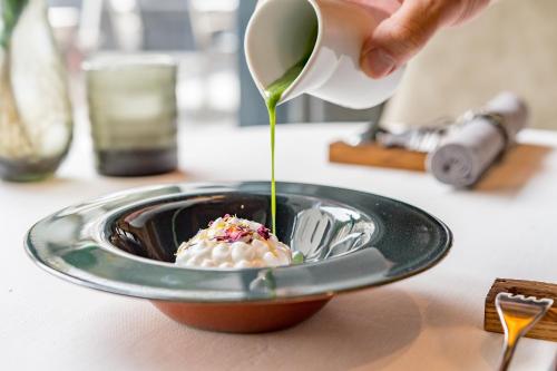 a person pouring sauce into a bowl of food at Sport- und Genusshotel Silvretta in Ischgl