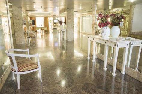 um quarto com uma cadeira branca e uma mesa com vasos em Flat Privativo Sol Victoria Marina em Salvador