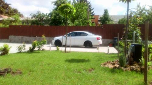 a white car parked in a yard next to a fence at Borostyán Vendégház Eger in Eger