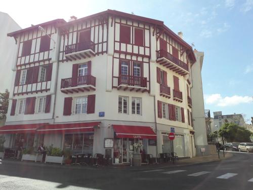 een groot wit gebouw met rode luiken op een straat bij Erdian in Biarritz