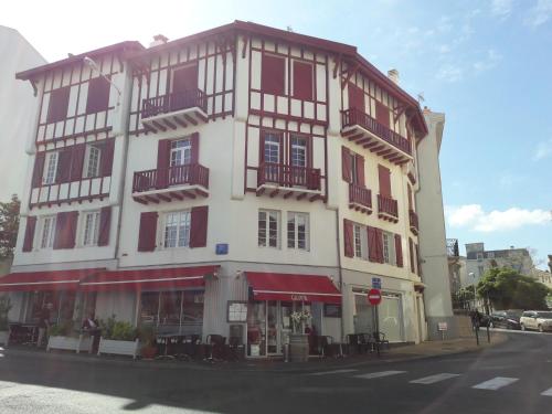 un grand bâtiment blanc avec volets rouges dans une rue dans l'établissement Erdian, à Biarritz