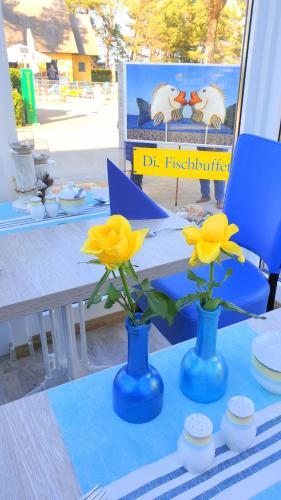 two blue vases with yellow flowers on a table at Vineta Strandhotels in Zinnowitz