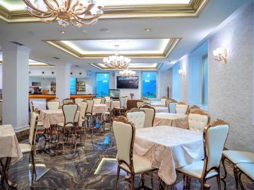 una sala da pranzo con tavoli, sedie e lampadario a braccio di Hotel Boka a Tirana