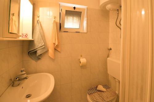 uma casa de banho branca com um lavatório e um WC em One bedroom apartment near the Kamenjak park in Prematura em Premantura