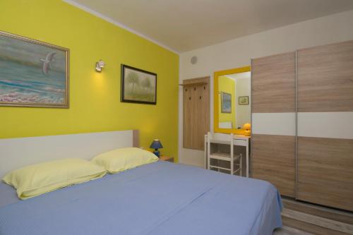 a bedroom with a bed and a yellow wall at One bedroom apartment near the Kamenjak park in Prematura in Premantura