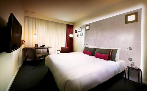 インバネスにあるpentahotel Invernessのピンクの枕が付く大きな白いベッドが備わるホテルルームです。