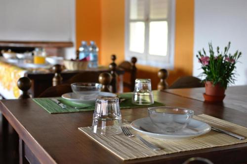 einem Holztisch mit Tellern und Gläsern darauf in der Unterkunft Fattoria del pino in Miasino