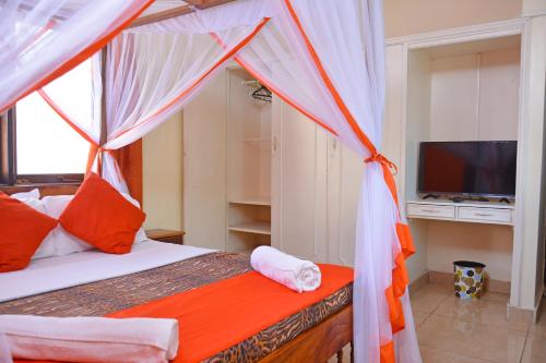 a bedroom with a canopy bed and a television at Ocean View Nyali Boutique Hotel in Nyali
