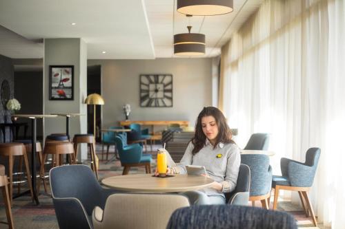 a woman sitting at a table in a restaurant at Novotel Ipswich Centre in Ipswich