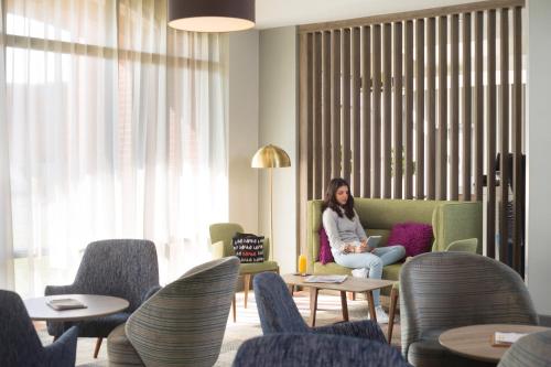 a woman sitting on a couch in a room with chairs at Novotel Ipswich Centre in Ipswich