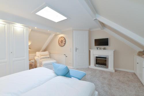 a white room with a bed and a fireplace at Alte Mühle direkt am Wattenmeer in Keitum