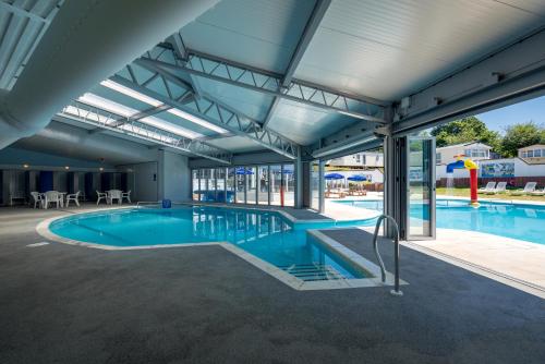 uma grande piscina interior com água azul num edifício em Camping Pods, Golden Sands Holiday Park em Dawlish