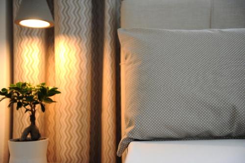 uma almofada numa cama ao lado de um vaso de plantas em Stamatia Apartments em Asprovalta