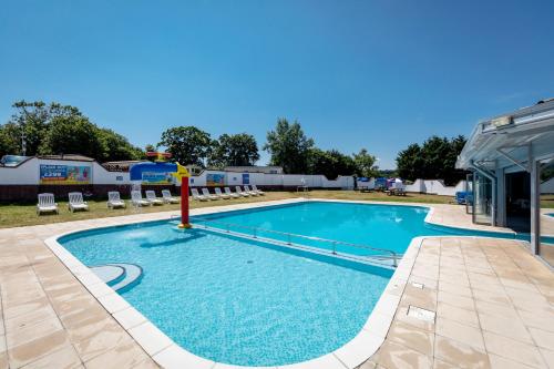 a pool at a resort with chairs and a building at Camping Pods, Golden Sands Holiday Park in Dawlish