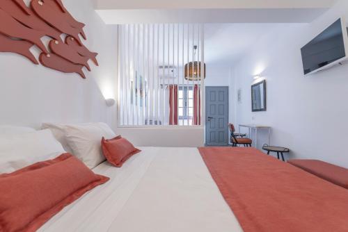 a bedroom with a large white bed and a television at Black Coast Santorini in Perivolos