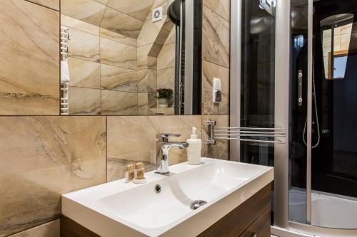 a bathroom with a sink and a shower at TatryTop Apartamenty Zaciszne in Zakopane