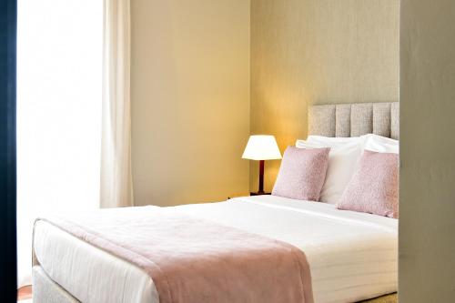 a bedroom with a large white bed with pink pillows at Central Monchique Hotel - Villa Termal Spa Resort - by Unlock Hotels in Monchique