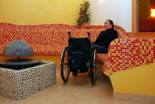 a man sitting on a couch with a wheelchair in a room at Gasthaus-Landhotel Traunstein in Abtenau