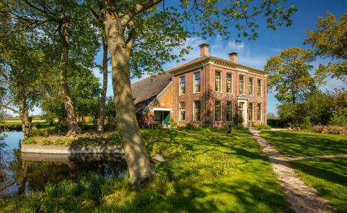 a large brick building with a pond in front of it at Bed and Breakfast Batenborg in Winsum