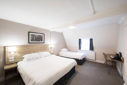 a hotel room with two beds and a window at Half Moon, Sherborne by Marston's Inns in Sherborne