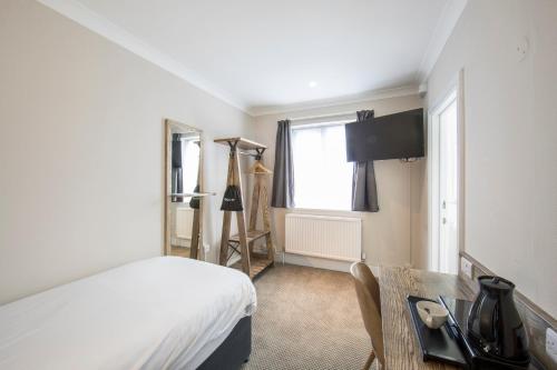 a bedroom with a bed and a desk and a window at Half Moon, Sherborne by Marston's Inns in Sherborne